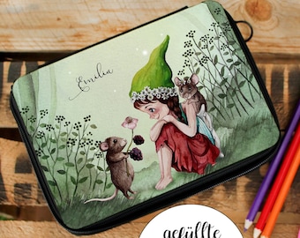 Puede incluir: Un estuche de lápices verde y rojo con una ilustración caprichosa de un hada con un sombrero verde y dos ratones. El texto "Emilia" está escrito en cursiva en el estuche. El estuche está etiquetado "gefuellte FEDERMAPPE".