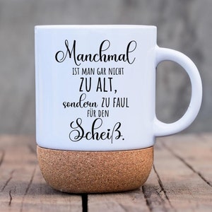 Könnte beinhalten: Weiße Keramiktasse mit Korkboden. Die Tasse hat schwarzen Text, der "Manchmal ist man gar nicht zu alt, sondern zu faul für den Scheiß." lautet.