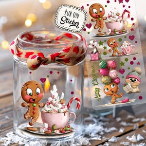 Könnte beinhalten: Ein klares Glas mit einem rot-braunen Band um die Oberseite. Das Glas hat einen Lebkuchenmann und eine rosa Tasse mit Schlagsahne und einem Zuckerstangen-Design. Ein durchsichtiges Stickerblatt mit Lebkuchenmännern und Weihnachtsdekorationen ist sichtbar.