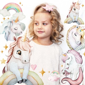 Puede incluir: Una niña joven con cabello largo y rubio lleva una camisa blanca con un diseño de unicornio. La camisa presenta un arcoíris, estrellas y varios unicornios en estilo acuarela.