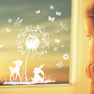 Puede incluir: Una silueta blanca de un diente de león con un ciervo y un conejo debajo. La imagen está en una ventana con un niño mirando la escena.