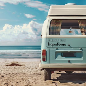 May include: A blue and white vintage camper van parked on a sandy beach. The back window has a black vinyl sticker that reads "Das Leben ist zu kurz f&uuml;r Irgendwann".