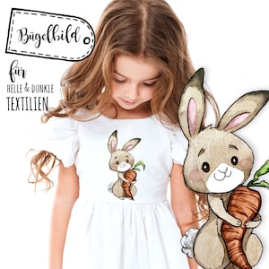 Op de afbeelding: Een aquarel-illustratie van een bruin konijn dat een wortel vasthoudt. Het konijn heeft grote ogen en een schattige glimlach. De illustratie is op een wit T-shirt.
