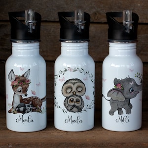 Könnte beinhalten: Drei weiße Edelstahl-Wasserflaschen mit schwarzen Deckeln und einem Strohhalm. Jede Flasche hat ein anderes Tierdesign: ein Reh, eine Eule und ein Elefant. Die Flaschen sind mit den Namen "Moola", "Moola" und "Milli" beschriftet.