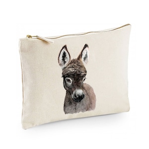 Puede incluir: Una bolsa de lona beige con cremallera con una ilustración de acuarela de la cabeza de un burro marrón.