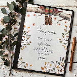 May include: A black binder with the German text "Zeugnisse" and a quote. The cover features a watercolour illustration of a birch tree branch with a child's legs and feet dangling down. Decorative floral and leaf accents frame the text.