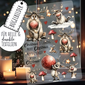 Könnte beinhalten: Eine transparente Folie mit Cartoon-Rentieren, Pilzen, Sternen und Herzen. Der Text lautet "Christmas is Coming", "Merry Christmas" und "I Need Cookies". Enthält auch den Text "BÜGELBILDER" und "FÜR HELLE & dunkle TEXTILIEN."