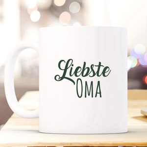 May include: White ceramic mug with a green cursive design that says "Liebste OMA".