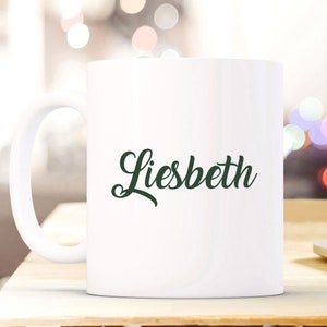 May include: White ceramic coffee mug with a green cursive name "Liesbeth" printed on the front.