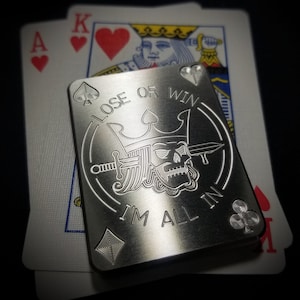 May include: A silver metal poker chip with a skull and crown design. The chip has the text "Lose or Win I'm All In" engraved on it.