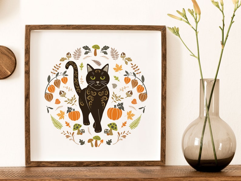 Black Cat Art Print shown in a dark wood frame.. Halloween Folk Art style Autumn Cat Wall Art. Scandinavian style illustration of a black cat surrounded by pumpkins, Chinese lanterns, leaves and berries, in warm autumn colours.