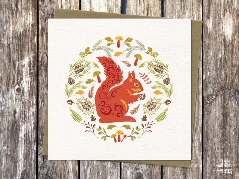 Square Card with Scandinavian style Squirrel illustration. Isle of Wight Red Squirrel surrounded by forest ferns, pinecones, toadstools and leaves, in bold, bright autumn colours capturing the spirit of Nordic Folk art.