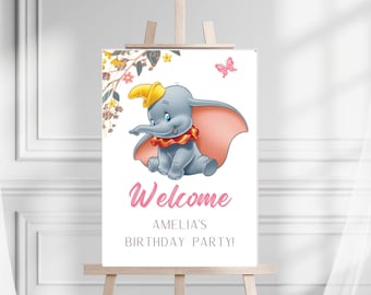 Puede incluir: Un cartel de bienvenida para una fiesta de cumpleaños con un dibujo animado de Dumbo el elefante y una mariposa rosa. El cartel dice "¡Bienvenido a la fiesta de cumpleaños de Amelia!"
