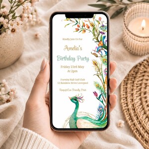 May include: A smartphone displaying a digital birthday invitation for Amelia. The design features a watercolour peacock and floral accents on a white background with text: Kindly Join Us For Amelia's Birthday Party Friday 23rd May At 2pm Formby Hall Golf Club 12 Rainbow Drive Liverpool Rsvp@Eco Friendly Print.