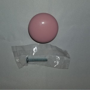 May include: A pink round cabinet knob with a silver screw.