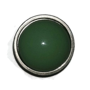 May include: A round, silver-toned button with a green, slightly domed center.