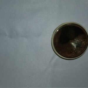 May include: A round, brown, wooden coaster with a light brown rim.