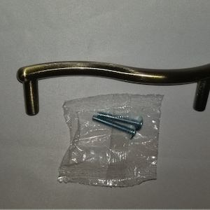 May include: A wavy, antique gold cabinet pull with a brushed finish. The pull comes with four screws for installation.