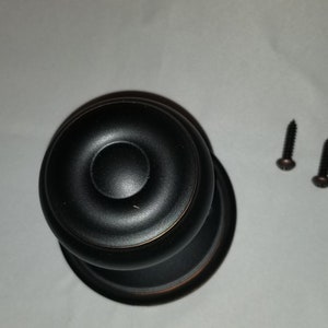 May include: A black round door knob with a decorative ring around the center. Two small black screws are included.