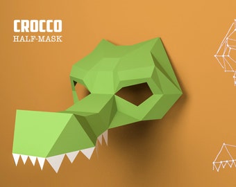 May include: Green papercraft crocodile half mask with white teeth. The mask is on a brown background with a white line drawing of the mask's outline.