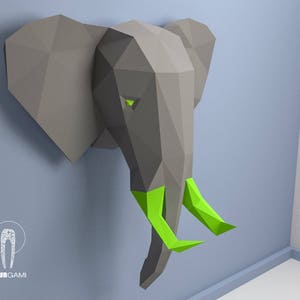Pode incluir: Uma cabeça de elefante de papel cinza com presas verdes. O elefante é um modelo 3D e está montado em uma parede.