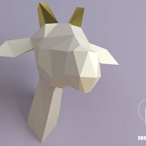 May include: A white papercraft goat head with gold horns. The goat head is made of folded paper and has a 3D effect.