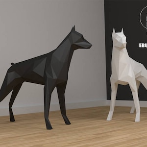 Puede incluir: Dos esculturas de perros de papel origami, una negra y otra blanca, de pie sobre un suelo de madera. Las esculturas están hechas de papel doblado y tienen un diseño geométrico. El fondo es una pared blanca y una pared negra con el texto "EBURGAMI" en blanco.