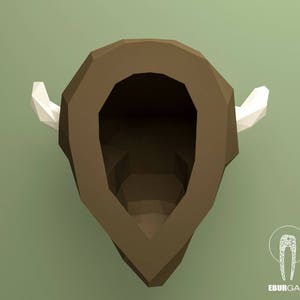 May include: A brown papercraft model of a bison head with white paper horns. The model is designed to be assembled by hand.