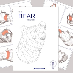 May include: A black and white line drawing of a bear head trophy. The bear's mouth is open and its teeth are visible. The drawing is on a white background with the text "THE BEAR TROPHY" above the drawing and "INSTRUCTIONS" below the drawing.