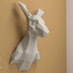 Pode incluir: Escultura de papel branco de uma cabeça de canguru montada em uma parede. A escultura é feita de papel dobrado e tem um design geométrico.