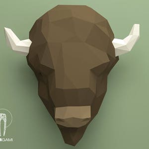 May include: A brown papercraft bison head with white horns. The bison head is made of folded paper and has a geometric design.