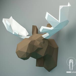 K&ouml;nnte beinhalten: Ein brauner Papier-Elchkopf mit wei&szlig;en Papier-Geweihen. Der Elchkopf besteht aus gefaltetem Papier und hat ein geometrisches Design.