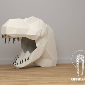 K&ouml;nnte beinhalten: Ein wei&szlig;er Papier-Dinosaurierkopf mit einem gro&szlig;en, offenen Maul und scharfen Z&auml;hnen. Der Dinosaurierkopf besteht aus gefaltetem Papier und hat einen 3D-Effekt. Der Hintergrund ist eine hellgraue Wand mit einem Holzboden.