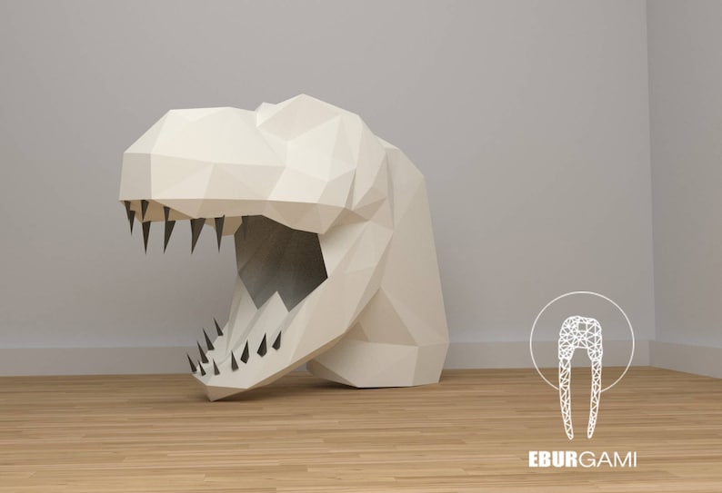 K&ouml;nnte beinhalten: Ein wei&szlig;er Papier-Dinosaurierkopf mit einem gro&szlig;en, offenen Maul und scharfen Z&auml;hnen. Der Dinosaurierkopf besteht aus gefaltetem Papier und hat einen 3D-Effekt. Der Hintergrund ist eine hellgraue Wand mit einem Holzboden.