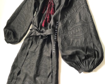 May include: A black linen dress with embroidered details and a red tassel tie. The dress has a cinched waist and long sleeves with a gathered cuff. #ETNO_STYLEINUA