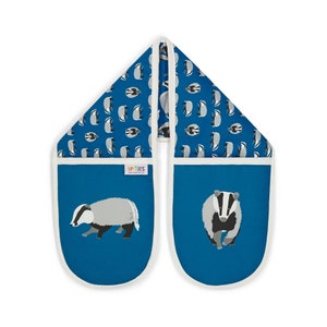 May include: A pair of blue oven mitts with a white trim. The mitts feature a badger design on a blue background. The mitts are made by LP TIES.