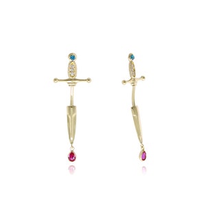 May include: A pair of gold earrings with a sword design. Each earring features a blue gemstone at the top of the sword and a red gemstone dangling from the bottom.