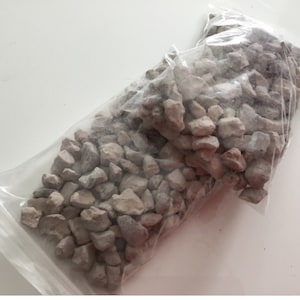 May include: A clear plastic bag filled with small, grey, irregularly shaped stones.