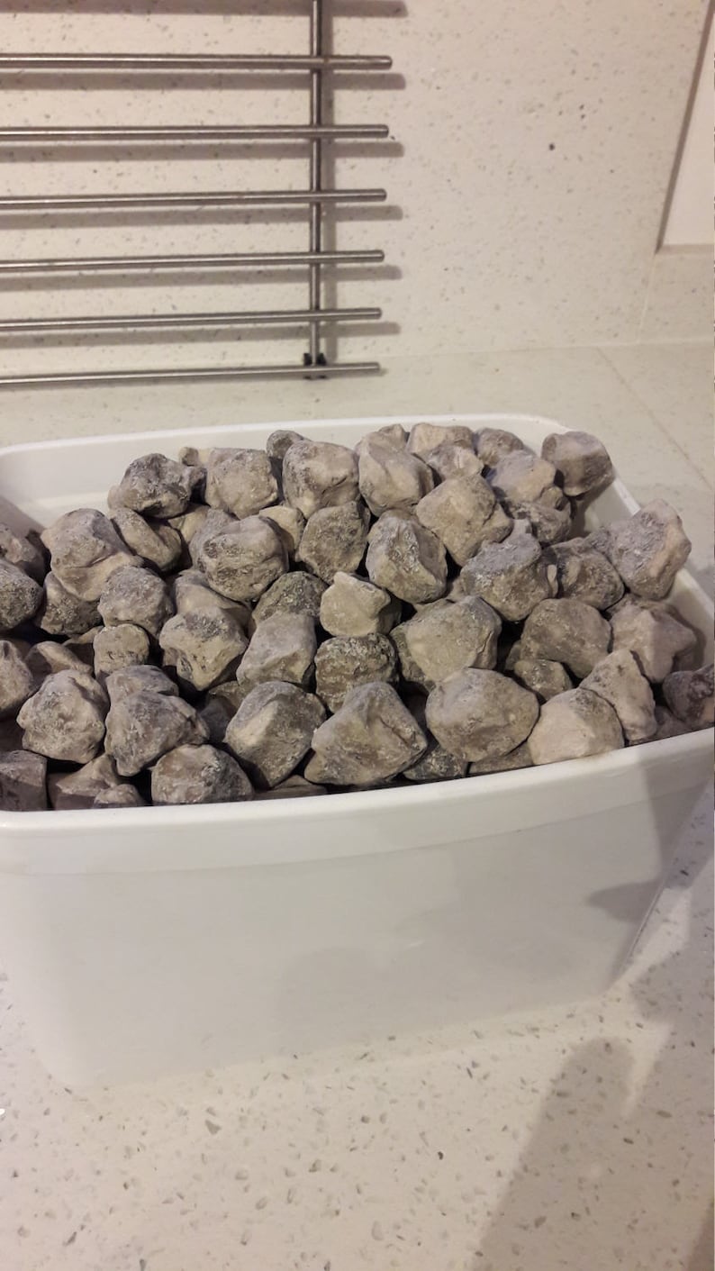 以下が含まれることがあります： 白いプラスチック製の容器に、灰色と茶色の石が詰められています。石は不規則な形をしていて、ざらざらした質感です。