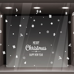 Può includere: Una vetrina di negozio decorata con adesivi bianchi a tema natalizio, tra cui fiocchi di neve, stelle, renne, Babbo Natale e un omino di pan di zenzero. Il testo "Buon Natale & Felice Anno Nuovo" è visualizzato al centro della vetrina.