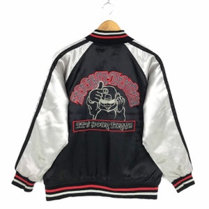 May include: Black satin bomber jacket with white sleeves and red and white striped trim. The back features an embroidered design with the words "BOOGIE DOWN!" and "IT'S YOUR TURN!!" in red.