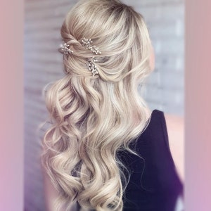 Puede incluir: Una mujer con el pelo largo, rubio y ondulado, peinado con un semi-recogido. El pelo se sujeta con dos peque&ntilde;as pinzas de pelo plateadas con detalles de perlas.