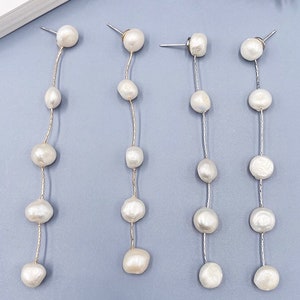 May include: Four pairs of long, silver chain earrings with white pearl beads. Each earring has a small pearl at the top and five larger pearls hanging down the chain.