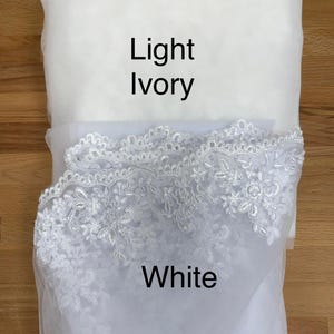 May include: Three fabric samples in ivory, light ivory, and white. The ivory sample is at the top, followed by light ivory, and white at the bottom. The white sample has a decorative lace trim. The colours are labelled with text.