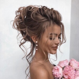 May include: A woman with long, brown hair styled in a high bun with loose curls. She is wearing pearl earrings and has a bouquet of pink peonies in her hand.