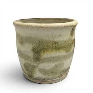 May include: A ceramic cup with a rounded rim and a tapered base. The exterior features a mottled glaze with horizontal bands of earthy green and off-white tones, showing a textured, speckled surface throughout the body of the vessel.
