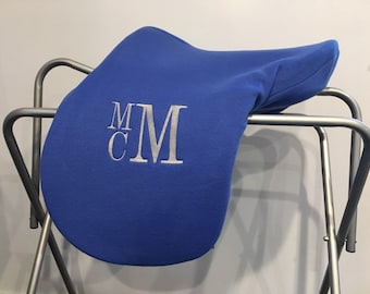 May include: A royal blue saddle pad with the monogram "MCM" embroidered in silver thread.