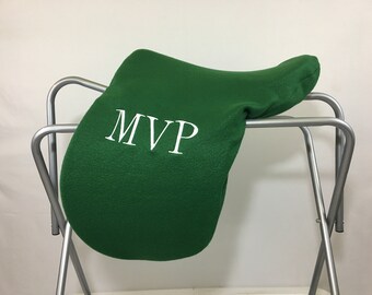 May include: Green saddle pad with the word "MVP" embroidered in white on a silver saddle stand.