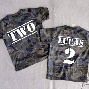 May include: Two camouflage t-shirts with white text. One shirt says "TWO" and the other says "LUCAS 2".
