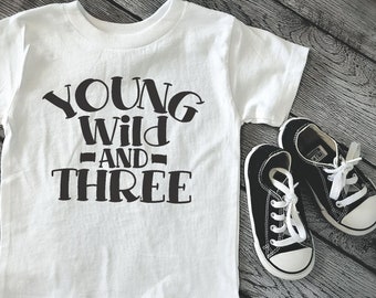 May include: White t-shirt with black text that reads "Young Wild and Three".
